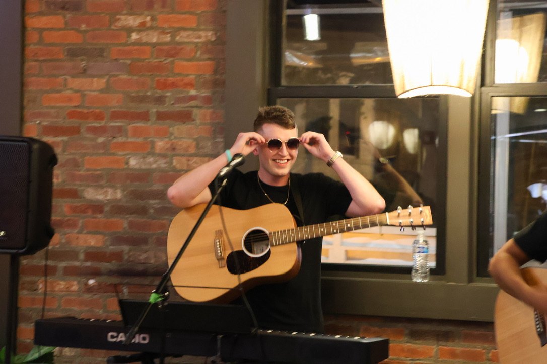 Conor Pederson on stage with acoustic guitar and sunglasses